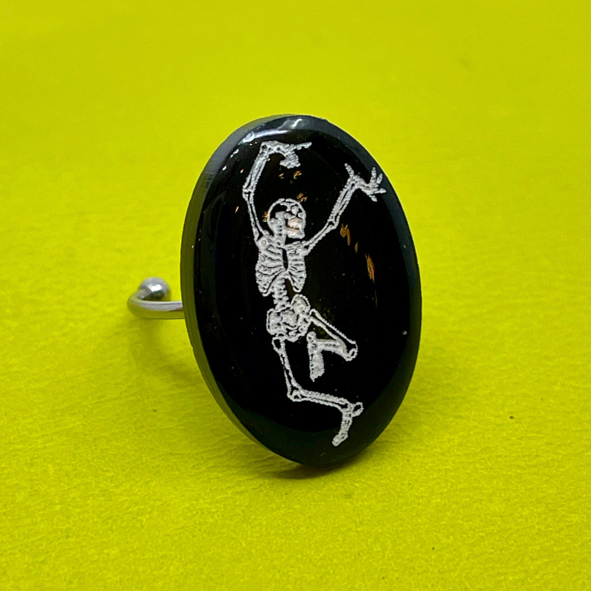 Black ring with a white skeleton design on a yellow background